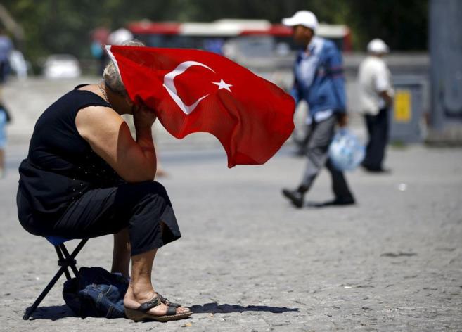 Una mujer sostiene una bandera turca mientras participa en una...