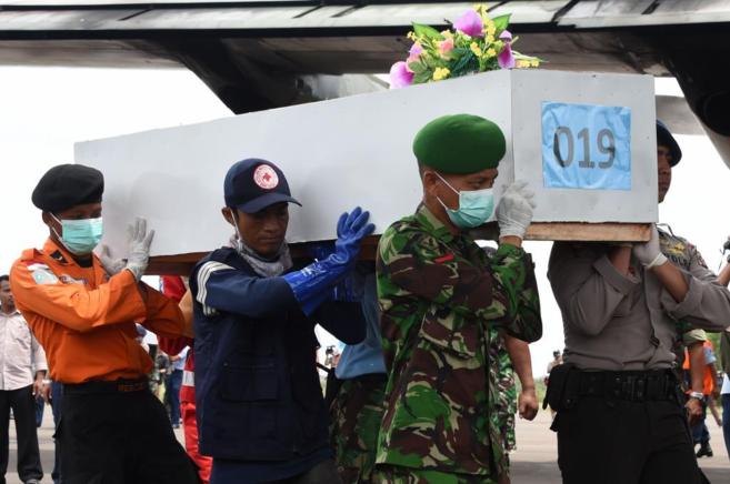 Miembros de los servicios de emergencia indonesios portan un atad...