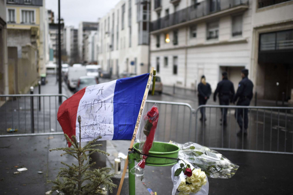 Flores y una bandera francesa frente a las oficinas del semanario...