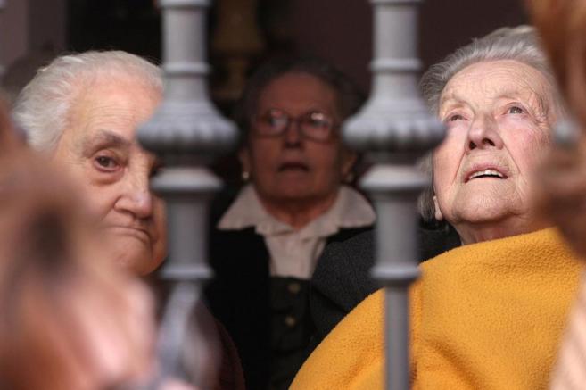 Tres ancianas observan en paso de una procesin en Sevilla.