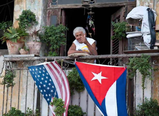 Una mujer saluda desde su balcon, donde cuelgan las dos banderas,...