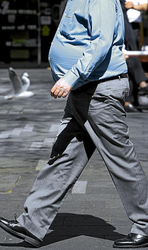 Un hombre con sobrepeso camina por la calle.