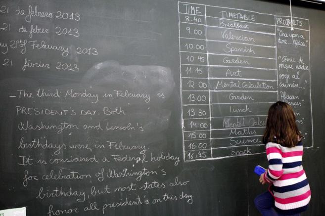 Una alumna escribe el horario en inglés en la pizarra de su colegio...