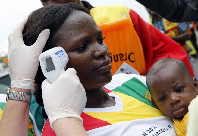 Una trabajadora toma la temperatura a una mujer y su hijo en Guinea