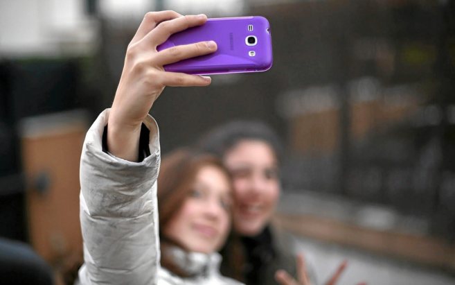 Dos niñas se hacen una fotografía con un móvil para difundirla a...