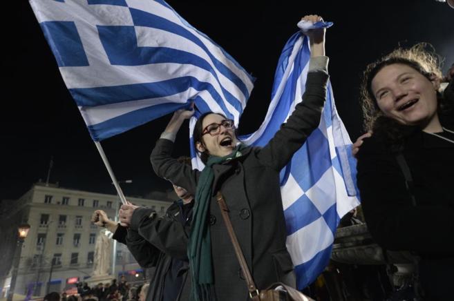 Activistas antiausteridad celebran en Atenas ondeando una bandera...