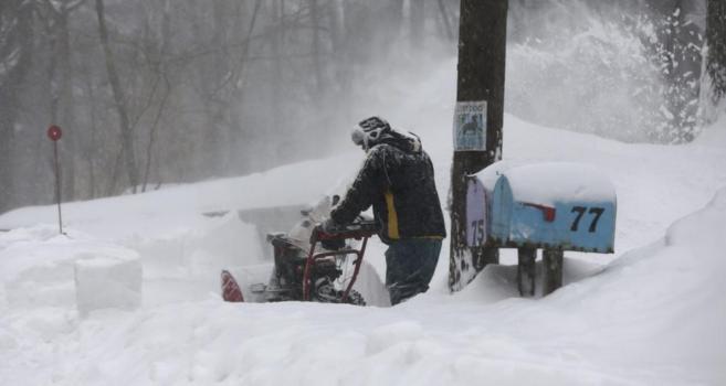 Un hombre utiliza una mquina para despejar de nieve un sendero a las...