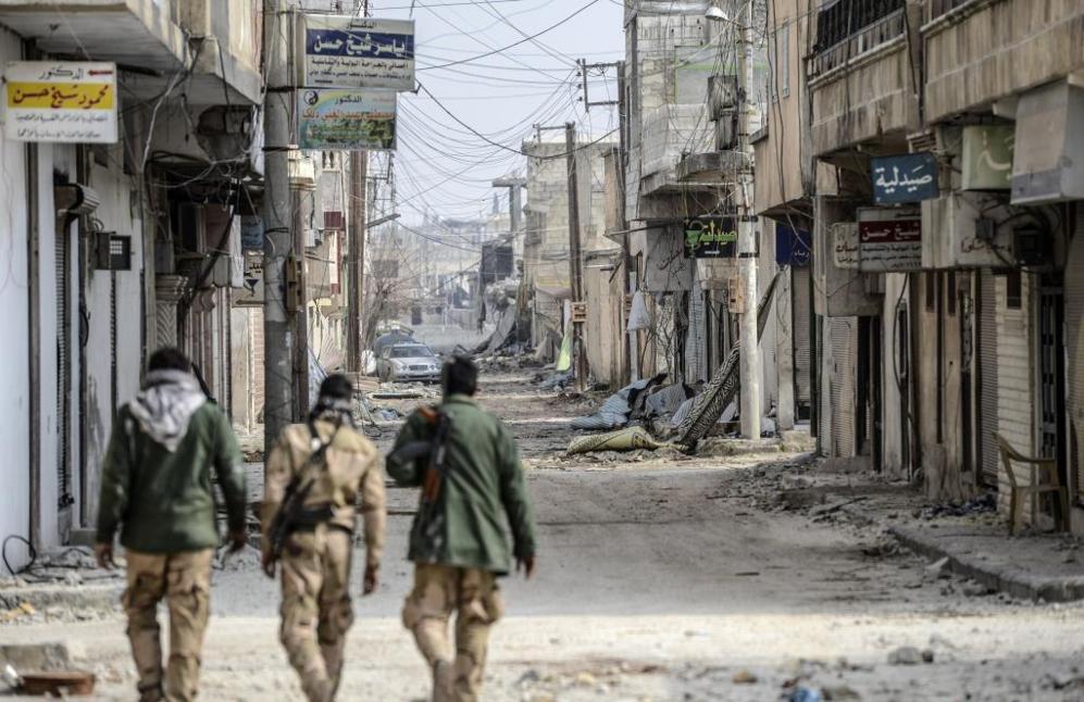 Soldados kurdos caminan por una calle destruida del centro de la...