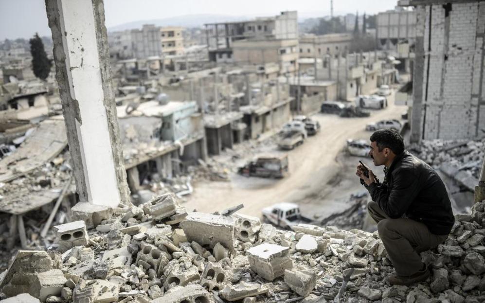 Un kurdo habla por radio mientras contempla desde lo alto de un...