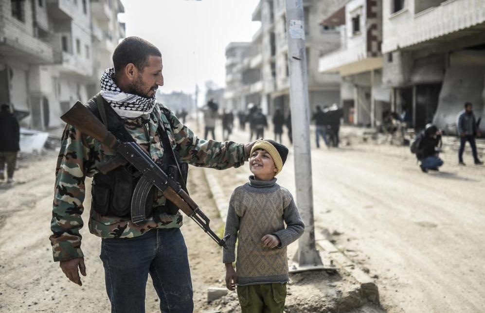 Un soldado kurdo acaricia a su hijo en una calle de Kobane.