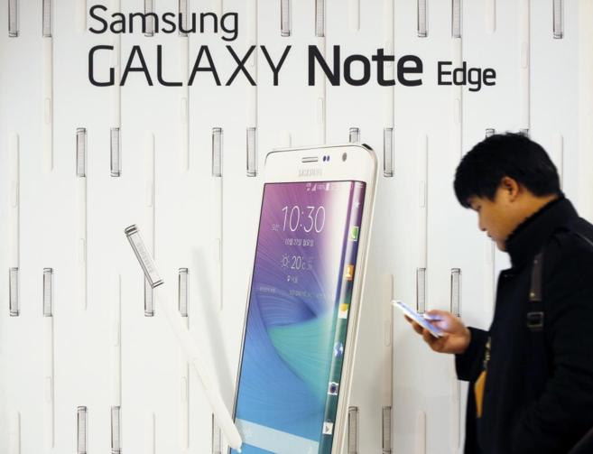 Un hombre mira su telfono Samsung junto a un cartel de la...