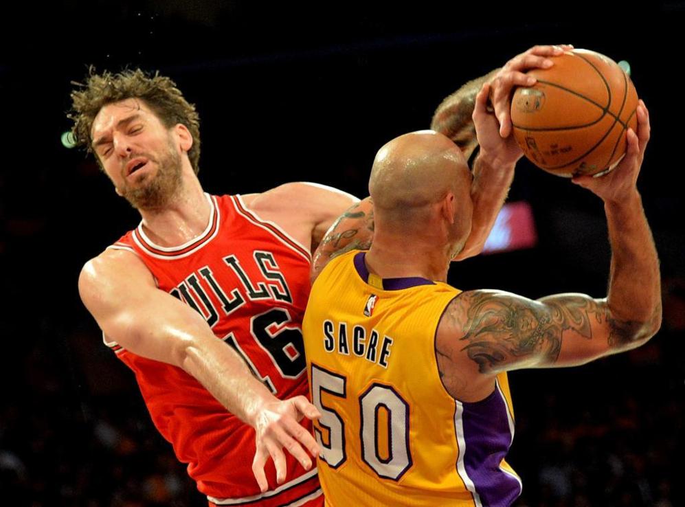 Robert Sacre of the Los Angeles Lakers (R) is blocked by Pau Gasol of...