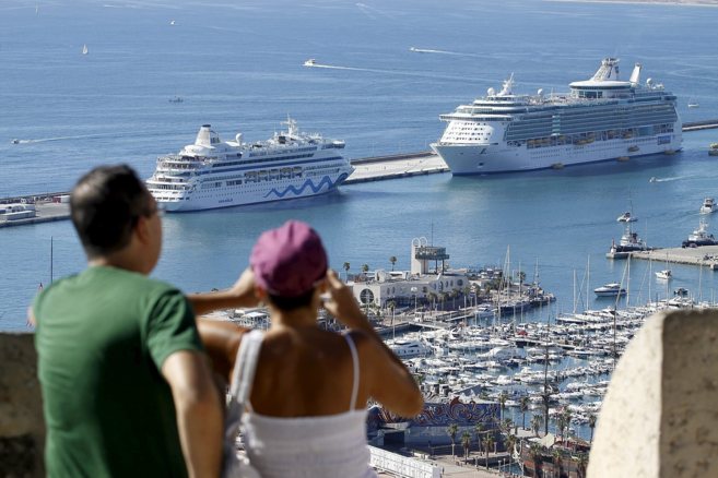 Dos personas observan los cruceros atracados en el Puerto de Alicante...