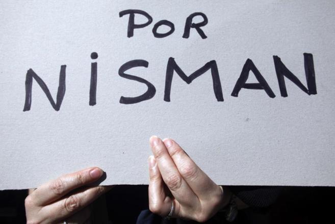 Una mujer levanta un cartel en memoria del fallecido fiscal argentino...