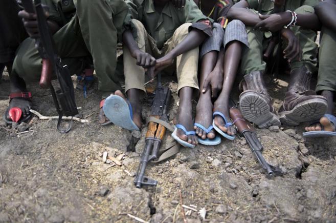 Varios niños soldado se sientan con sus fusiles en una ceremonia de...