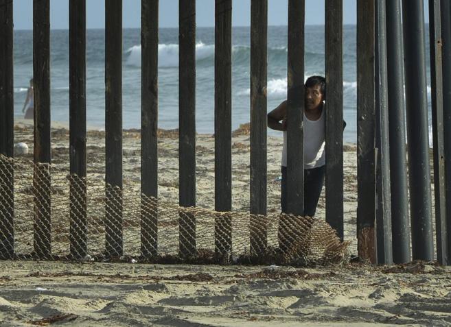 Un hombre mira hacia EEUU desde el lado mexicano de la valla, en San...