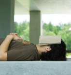 Un universitario reposa con un libro en la cara