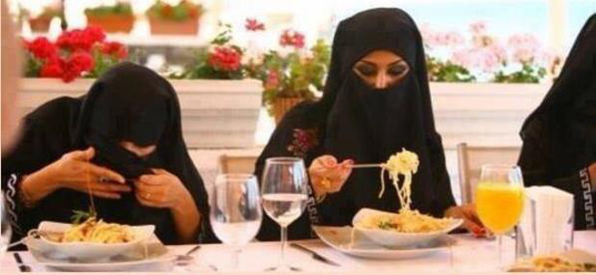 Mujeres con niqab teniendo dificultades para comer spaghetti.