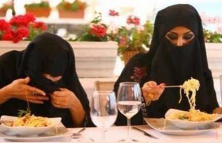 Mujeres con niqab teniendo dificultades para comer spaghetti.