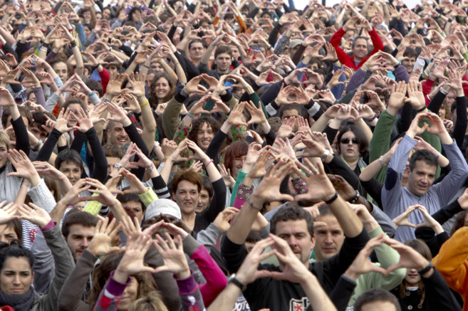 Cientos de personas alzan sus manos en una protesta contra la...