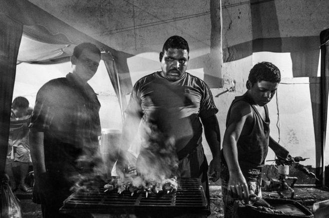 Un preso de la crcel de Vista Hermosa (Venezuela) cocina carne junto...