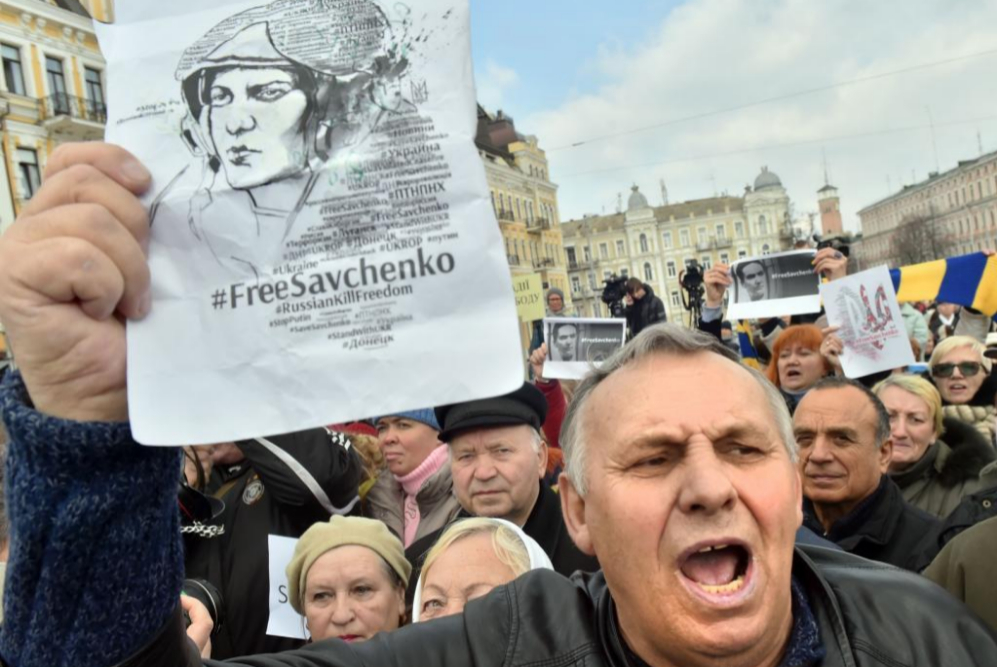 Un hombre sostiene un panfleto, mostrando la imagen de Nadia Savchenko...