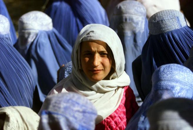 Una afgana con el rostro descubierto y rodeada de otras mujeres con...