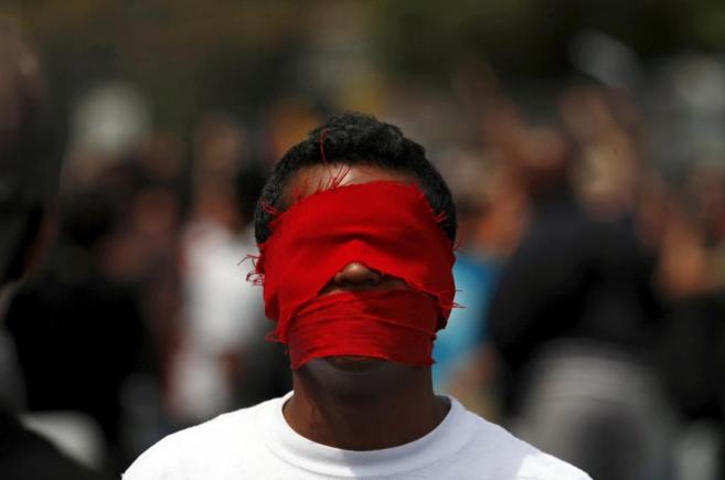 Un estudiante venezolano, con la cara tapada, en protesta por la...