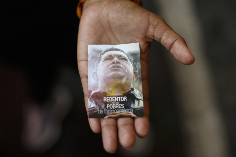 Una mujer lleva en la mano una estampa con el retrato de Hugo Chvez...