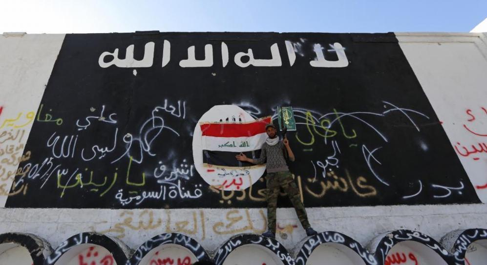 Un iraquí exhibe su armamento ante la bandera del Estado Islámico en...