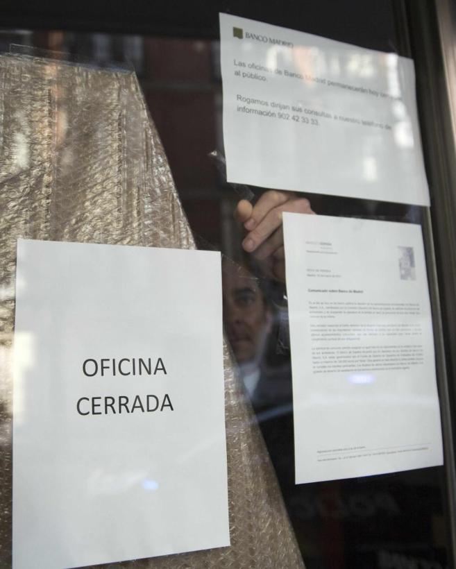 Un empleado de Banco Madrid pega el comunicado del Banco de Espaa.