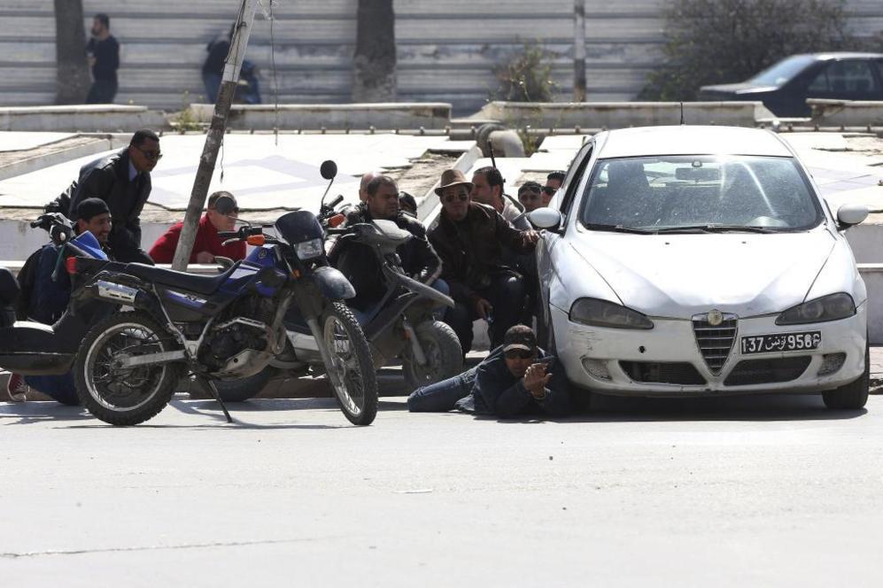 Agentes de la Polica tunecina toman posiciones detrs de un coche...