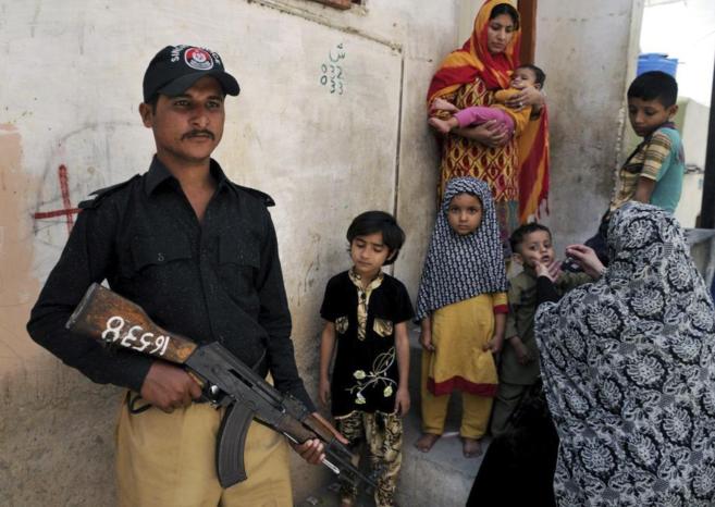Un agente de seguridad paquistan escolta a trabajadoras de un equipo...