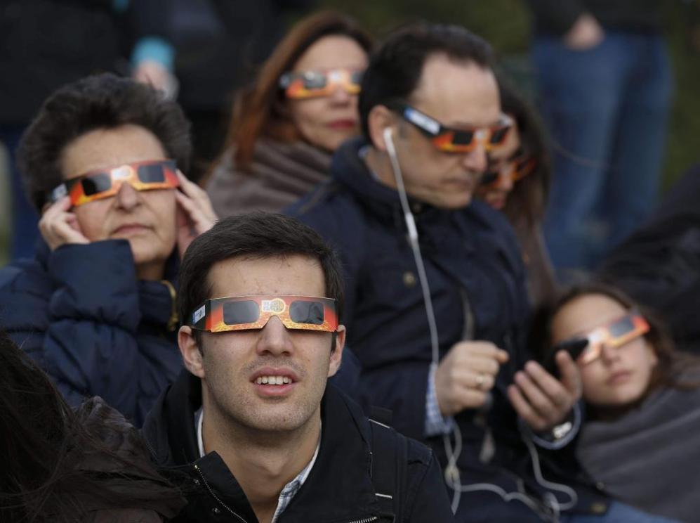 Varias personas observan el eclipse desde el Planetario de Madrid.