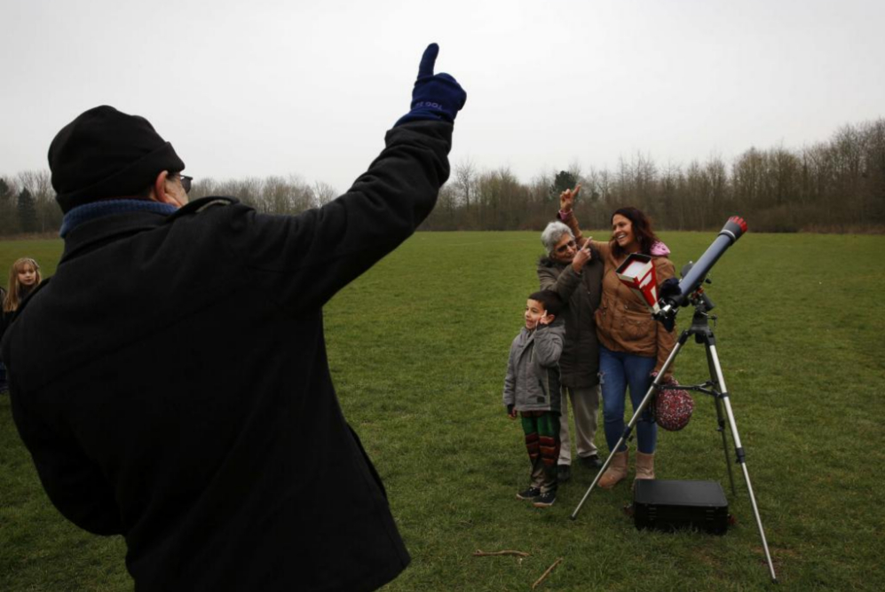 Familia posando frente a un telescopio antes de observar el eclipse en...