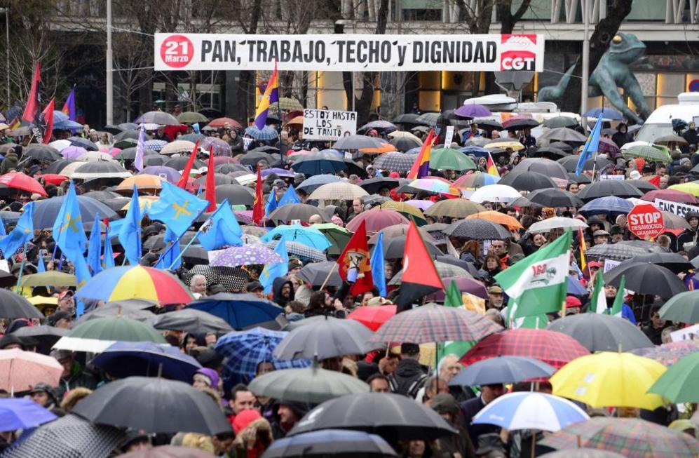 Varios manifestantes se protegen de la lluvia con paraguas durante las...