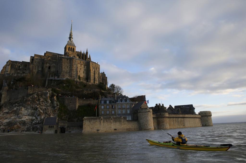 Un hombre navega en canoa en las aguas que rodean a Mont Saint-Michel...