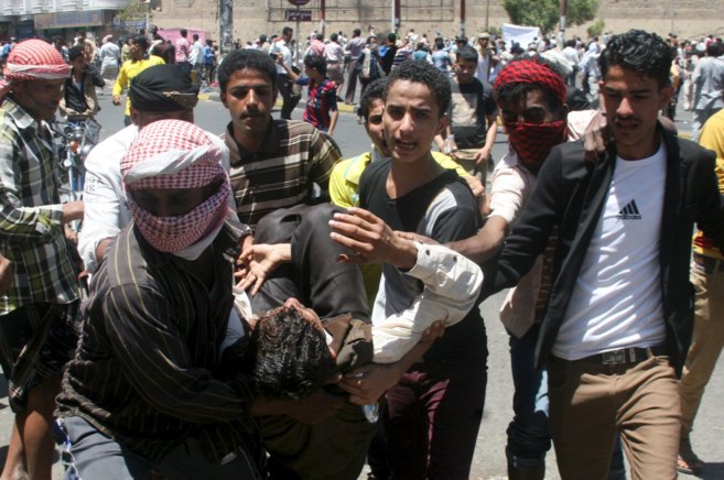 Manifestantes anti-Houthi cargan a un hombre herido en las protestas...