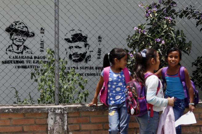 Varias nias en Colombia frente a dos grafitis de las FARC