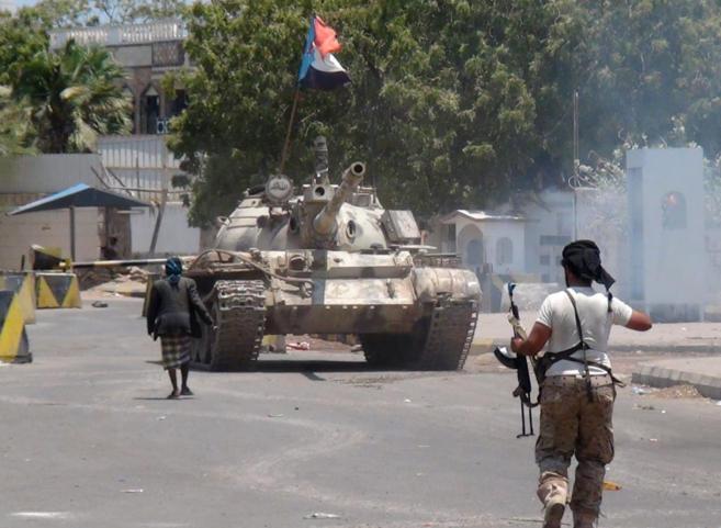 Hombres armados pasan junto a un tanque del grupo separatista Al Hirak...