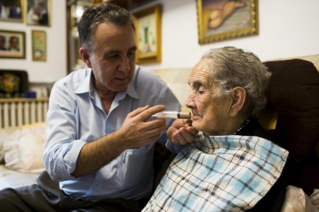 Una mujer con Alzheimer recibe los cuidados de un familiar.