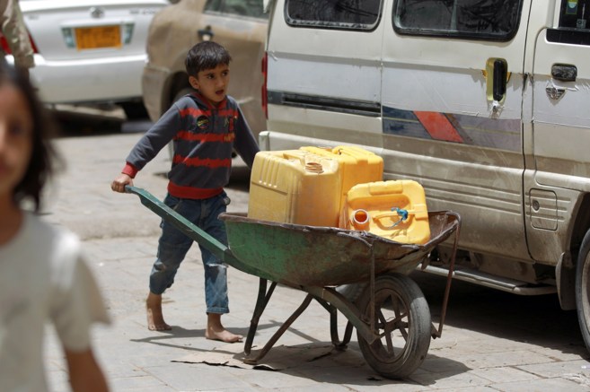 Un nio yemen lleva contenedores de agua en el casco antiguo de la...