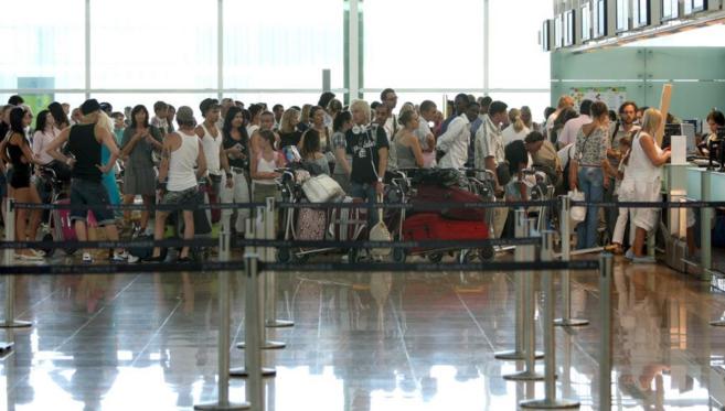 Decenas de viajeros hacen cola para facturar en la Terminal 1 del...