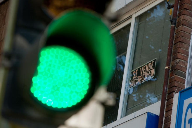 Imagen de archivo de un semforo en verde delante de un cartel de...