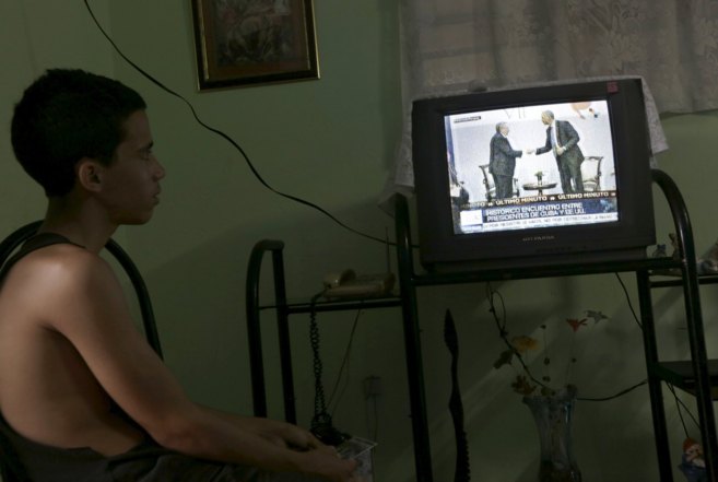 Un joven cubano sigue a travs de la televisin las noticias sobre...