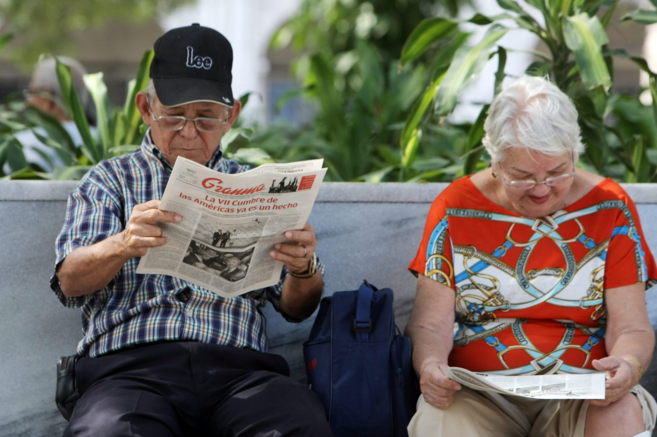 Una pareja lee un peridico cubano con informacin sobre la Cumbre...