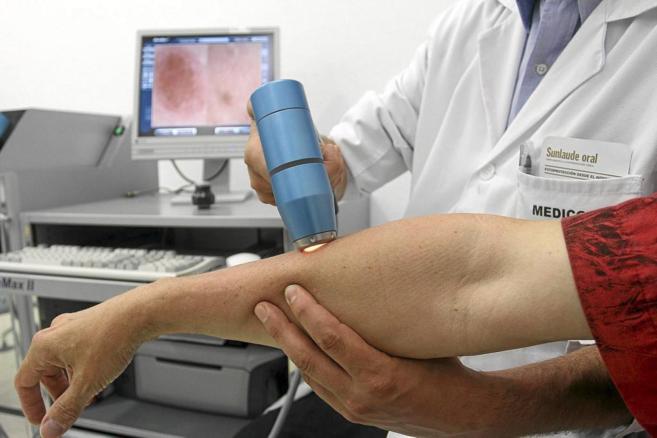 Un especialista usa un dermatoscopio para evaluar la piel de una...