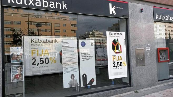 Escaparate de una oficina de Kutxabank, en Madrid, con varios carteles...