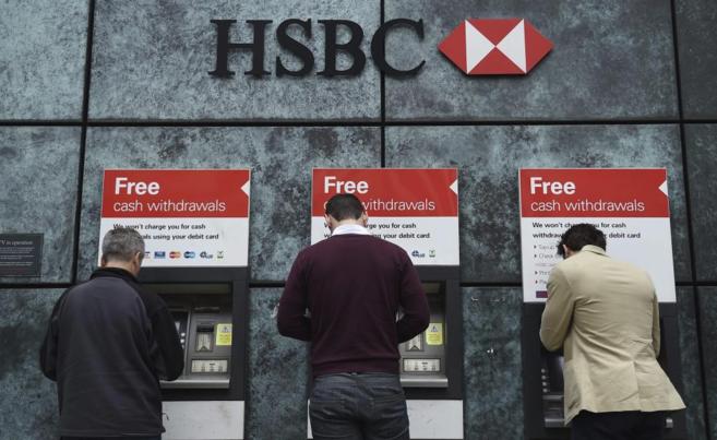 Tres clientes sacan dinero en los cajeros del banco HSBC en Londres...