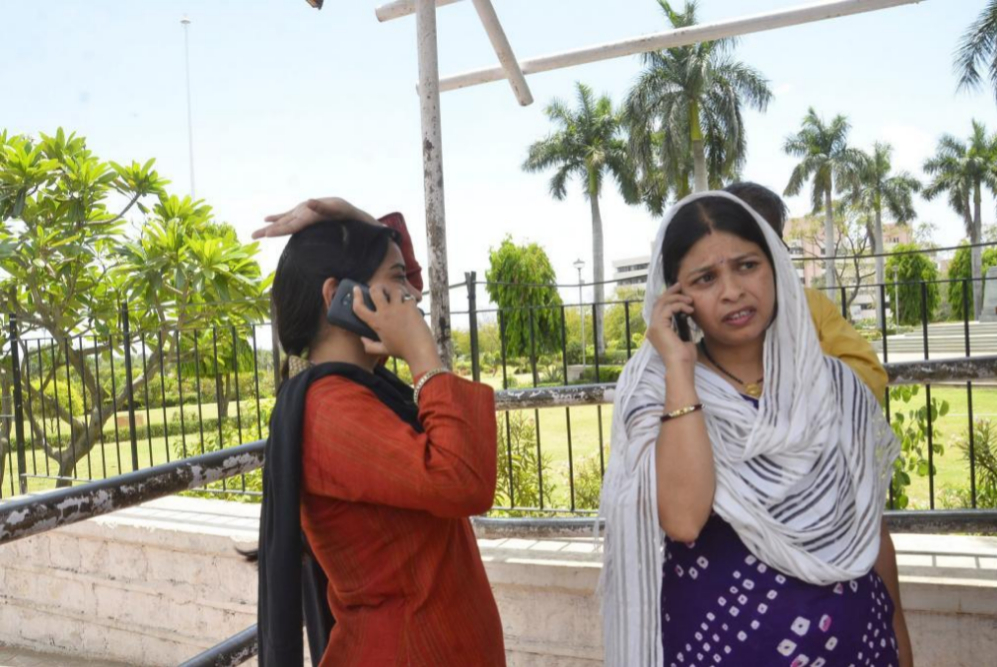 Mujeres indias hacen llamadas telefnicas al salir del edificio en el...